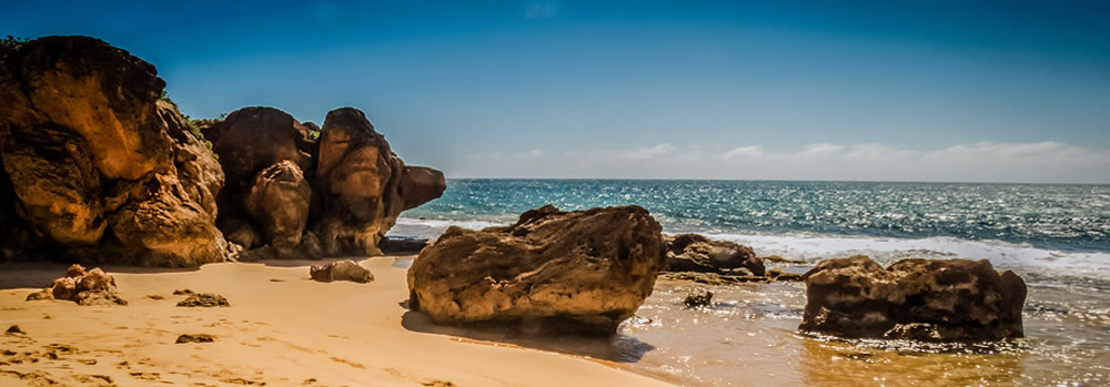 A beach with large rocks in the day.